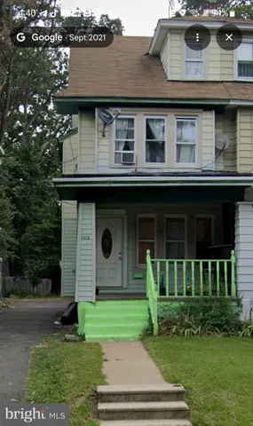 a brick house with a yard plants and large tree