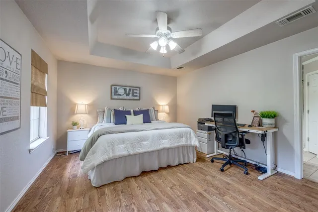 a spacious bedroom with a bed a desk and chair with wooden floor