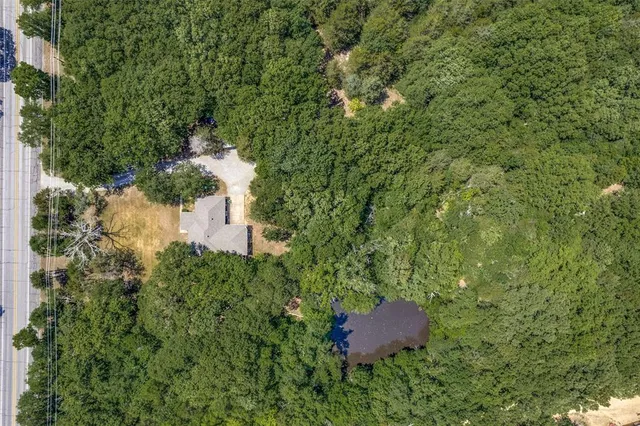 an aerial view of residential house with outdoor space and trees all around