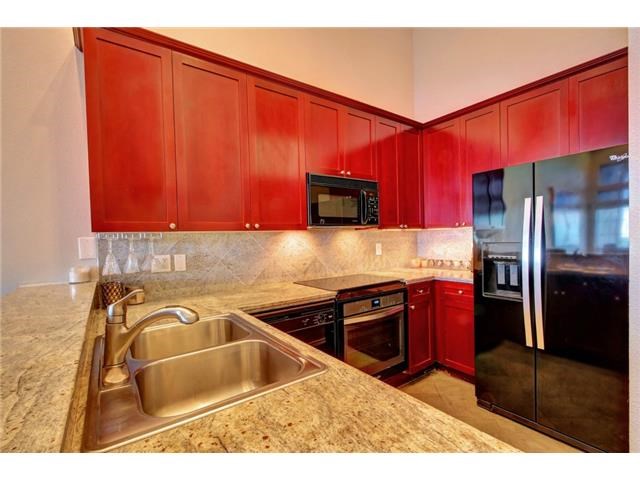 2918 Ranch Road 620, Unit K170 Austin, TX 78734 - Photo 3 of 22 A contemporary kitchen showcasing vibrant red cabinetry and sophisticated granite counters.