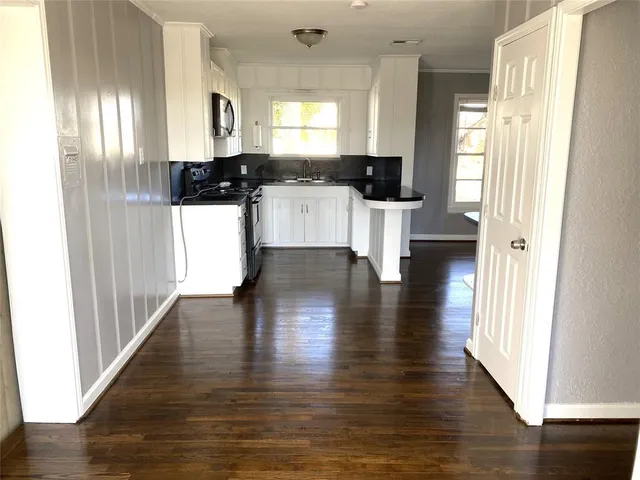 a kitchen with granite countertop a refrigerator a sink and white cabinets