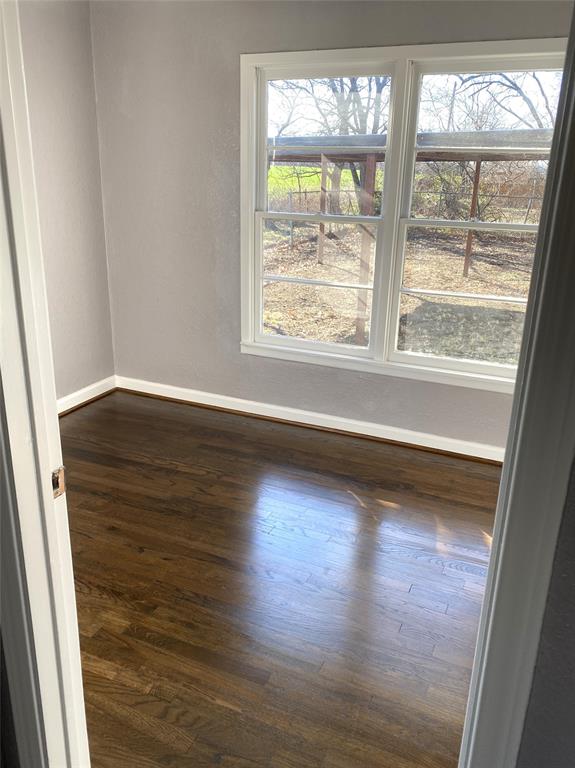 704 Scurlock Street Grandview, TX 76050 - Photo 7 of 11 a view of an empty room with wooden floor and a window