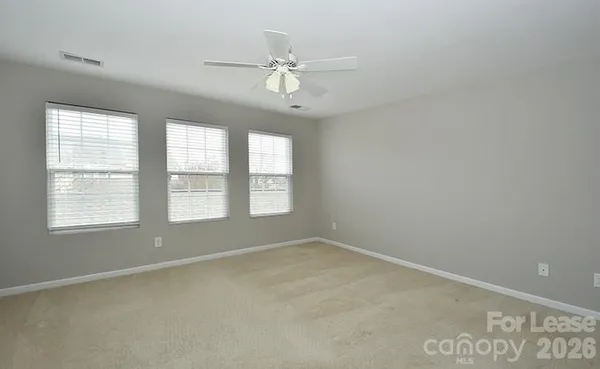an empty room with windows and fan