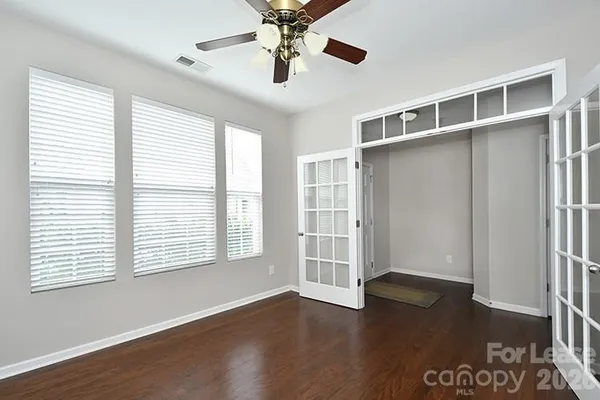 a view of an empty room with a window and wooden floor