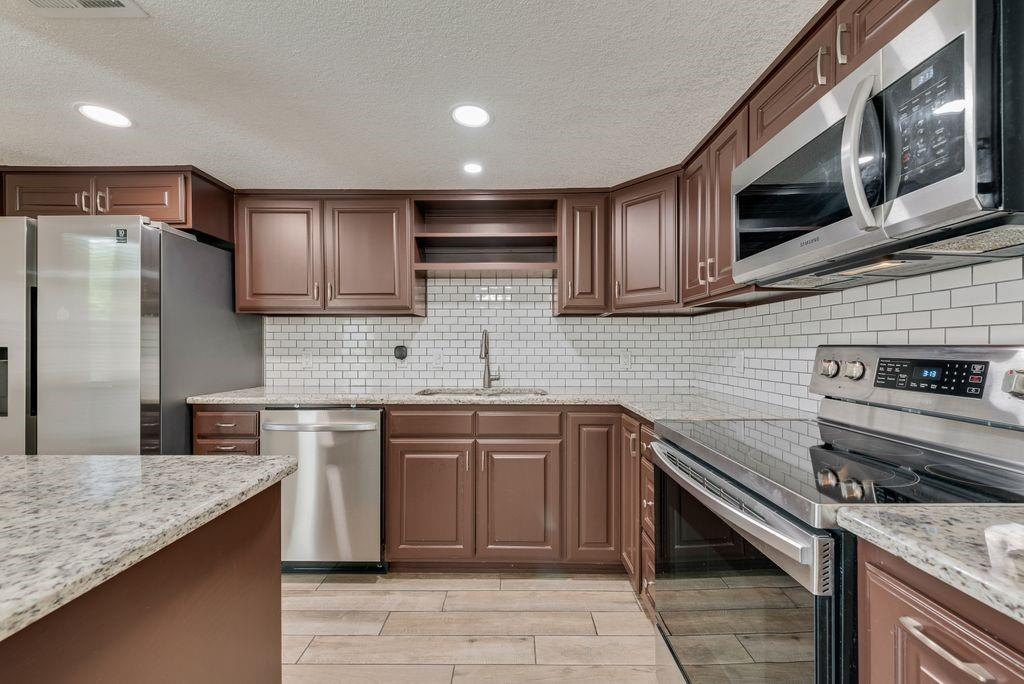 219 West Rochelle Road Irving, TX 75062 - Photo 10 of 29 Kitchen featuring wood-finish cabinetry, light-toned countertops, and a subway tile backsplash