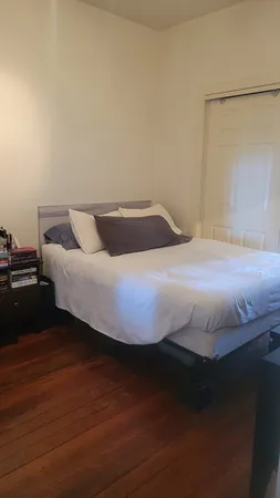 a bedroom with a bed and wooden floor