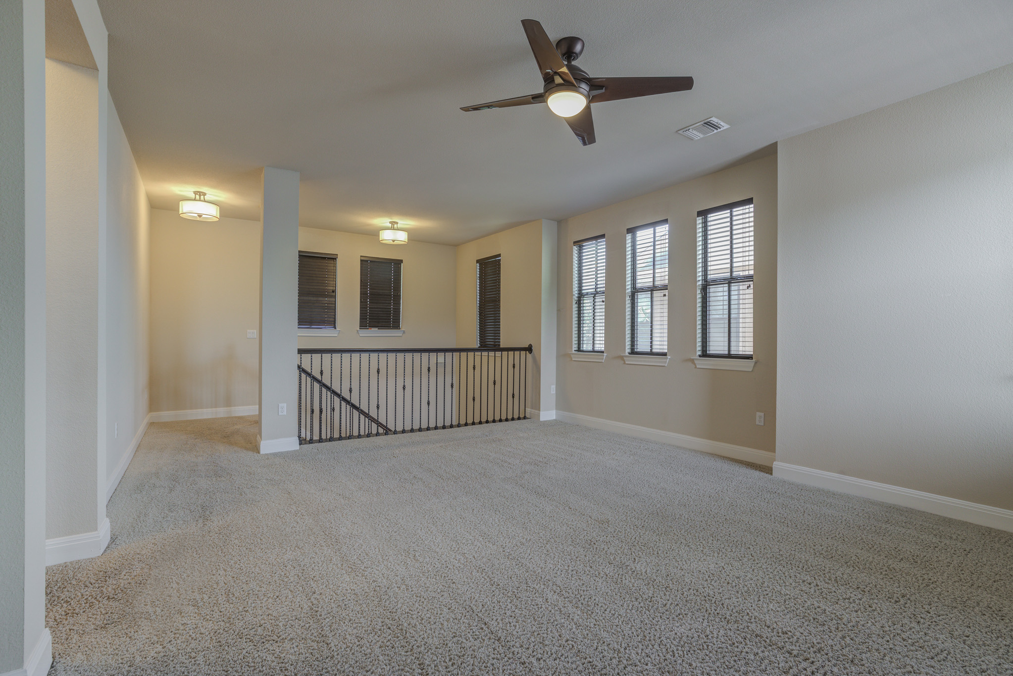 4524 Berkman Drive Austin, TX 78723 - Photo 26 of 38 Carpeted upstairs bonus room featuring a ceiling fan, three windows with blinds, and iron railing