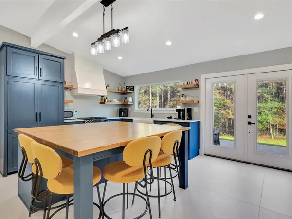 a kitchen with stainless steel appliances granite countertop a stove a refrigerator a sink a dining table and chairs with wooden floor