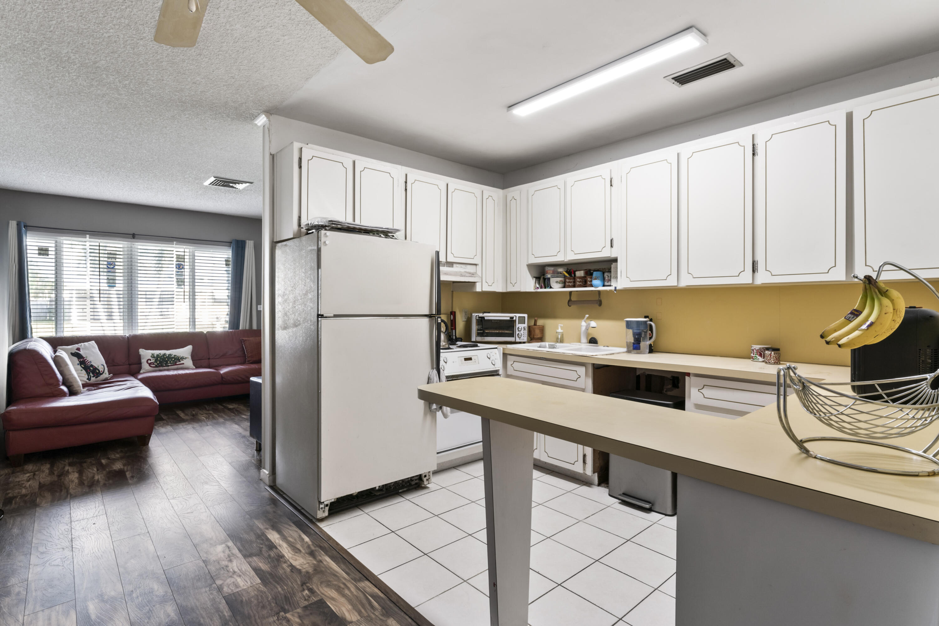 337 East Lake Road Palm Springs, FL 33461 - Photo 4 of 26 a kitchen with a refrigerator a stove a sink dishwasher and white cabinets with wooden floor