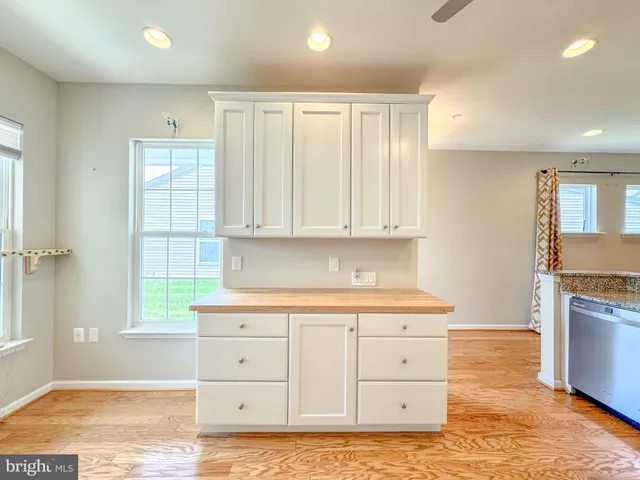 a kitchen with white cabinets and window