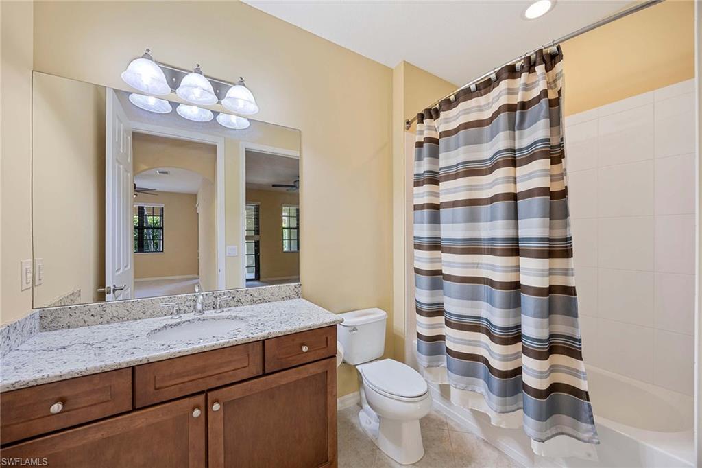 9036 Alturas Street, Unit 3603 Naples, FL 34113 - Photo 13 of 41 a bathroom with a granite countertop toilet a sink and a large mirror