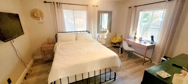 a bedroom with a bed a flat screen tv and a window