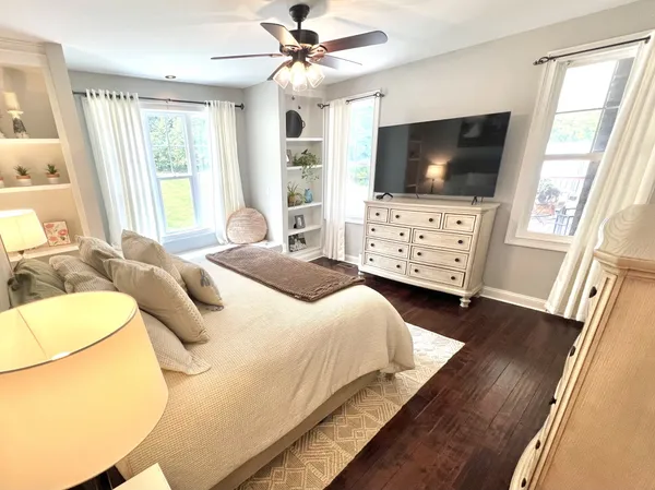 a bedroom with a flat screen tv on dresser and a table