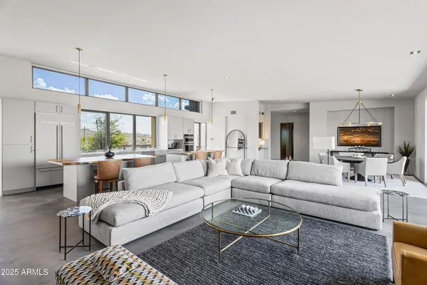 a living room with furniture a large window and kitchen view