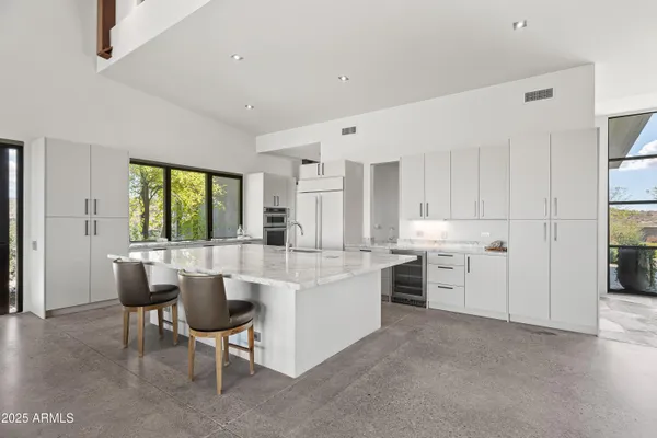 a large white kitchen with a sink and chairs