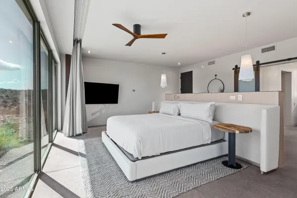 a bedroom with a bed lamp and a large window