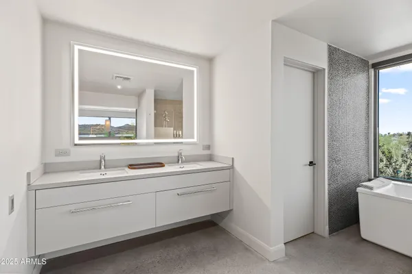 a bathroom with a double vanity sink a mirror and a bathtub