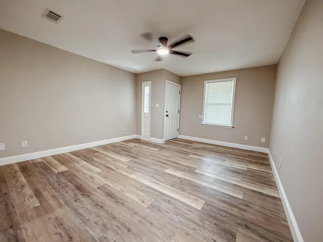 a view of empty room with wooden floor and fan