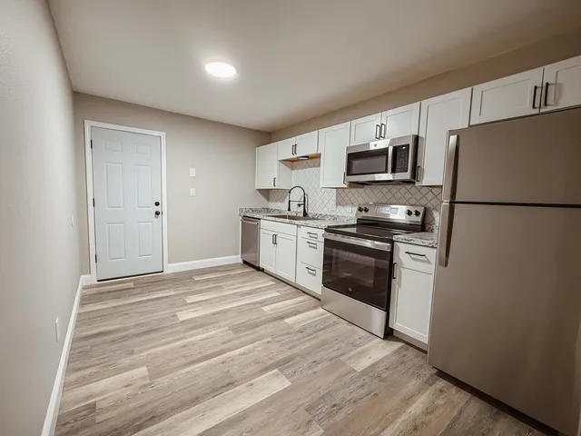 a kitchen with granite countertop a refrigerator stove top oven and sink