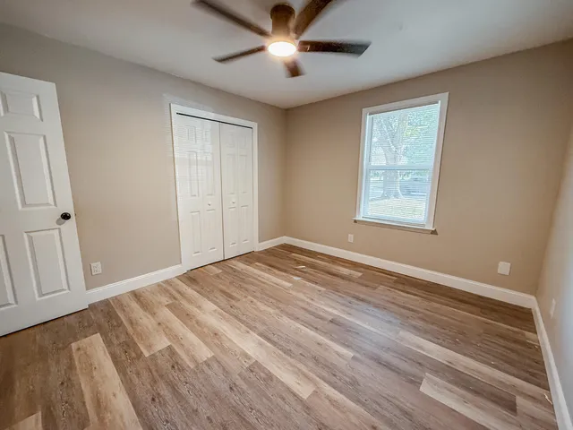 a view of empty room with wooden floor and fan