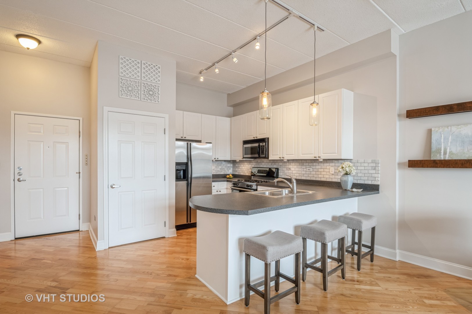 1301 West Washington Boulevard, Unit 405 Chicago, IL 60607 - Photo 3 of 10 a kitchen with stainless steel appliances granite countertop a stove a sink a microwave a refrigerator and white cabinets with wooden floor