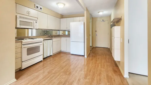 a kitchen with white cabinets and wooden floor
