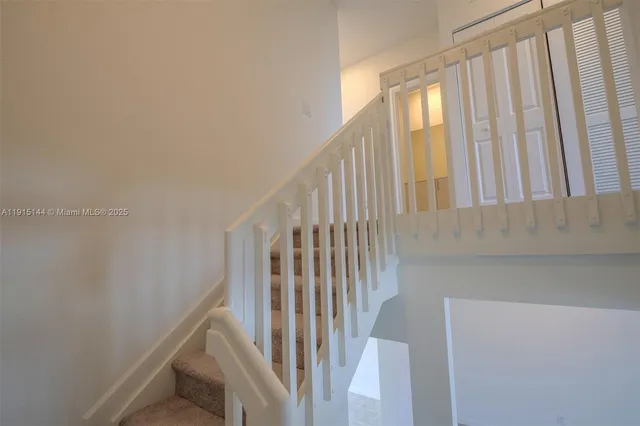 a view of staircase with railing and white walls