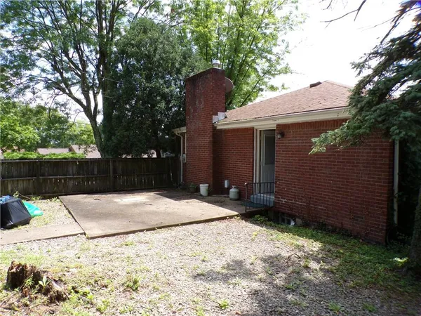 a backyard of a house with large trees and wooden fence