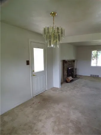 an empty room with a fireplace and chandelier fan
