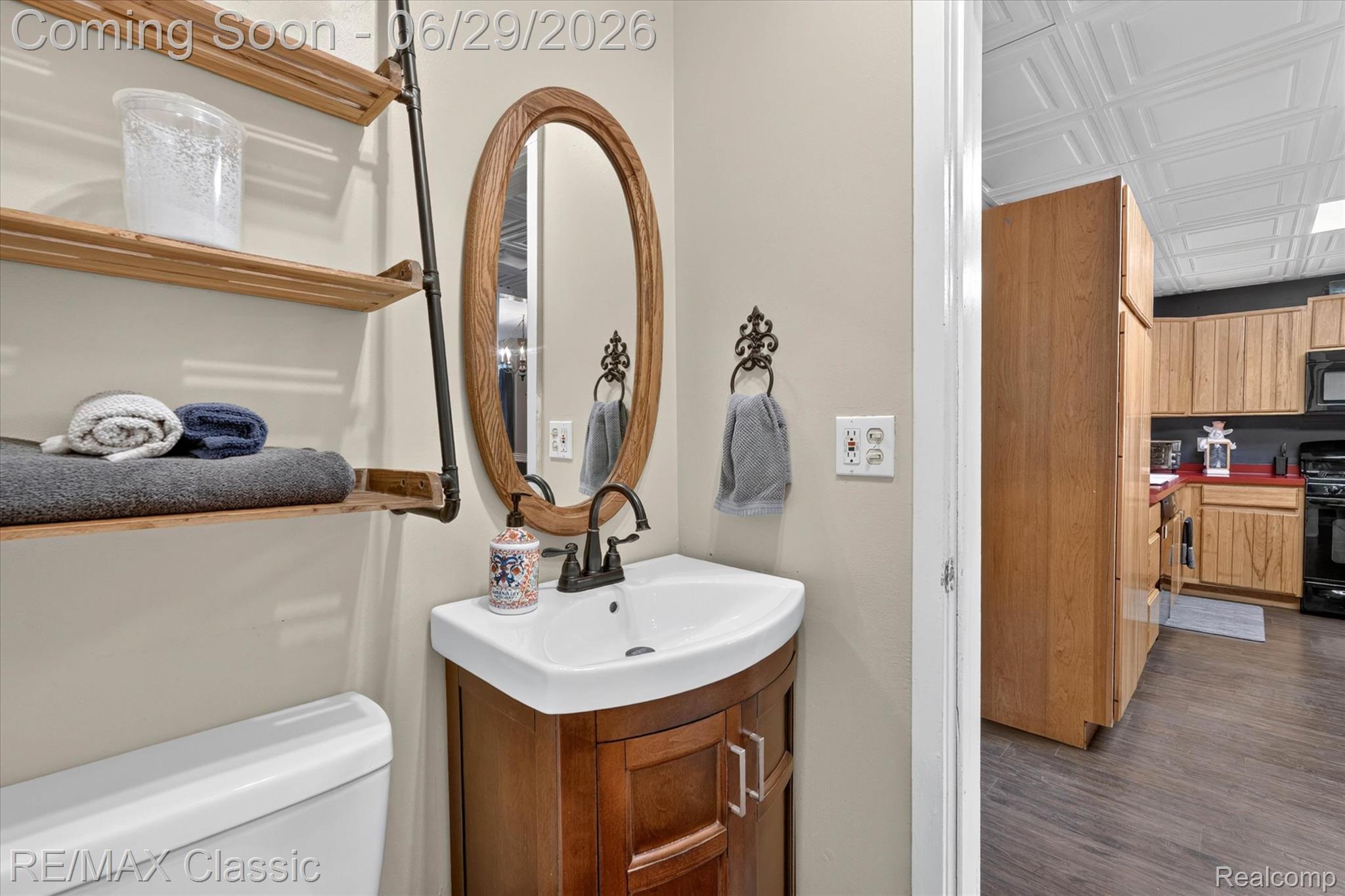352 Meribah Road Highland, MI 48356 - Photo 17 of 39 Bathroom featuring a corner vanity with a white basin sink, wood-finish cabinet, and an oval wood-framed mirror