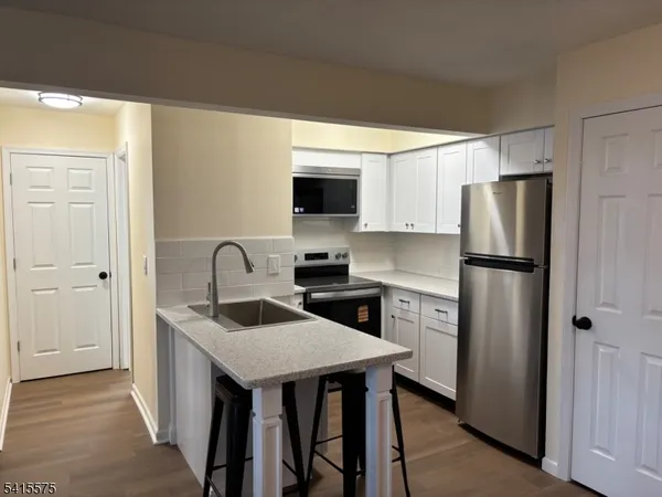 a kitchen with stainless steel appliances granite countertop a refrigerator a sink a stove and a refrigerator