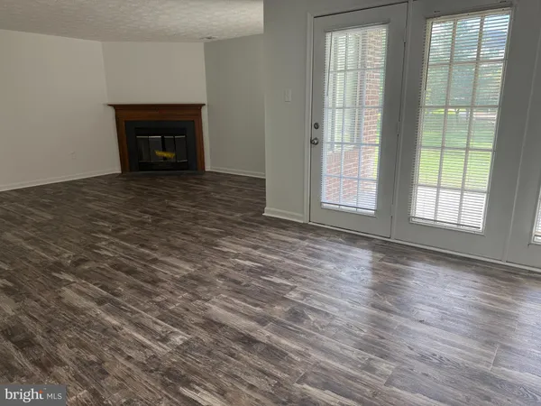 an empty room with wooden floor fireplace and windows