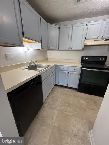 a kitchen with granite countertop a stove top oven sink and cabinets