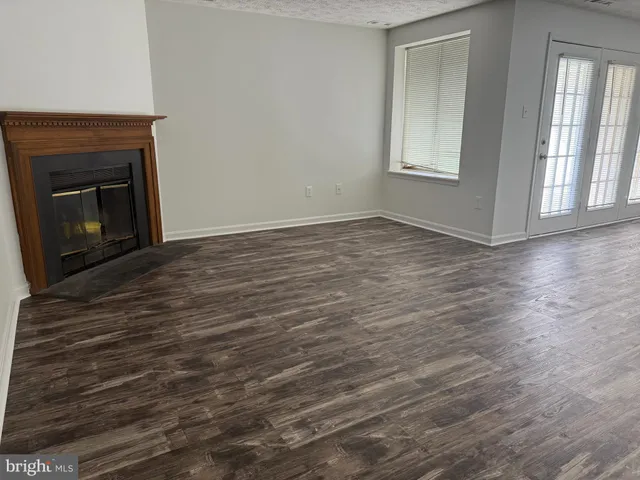 a view of empty room with wooden floor and fireplace
