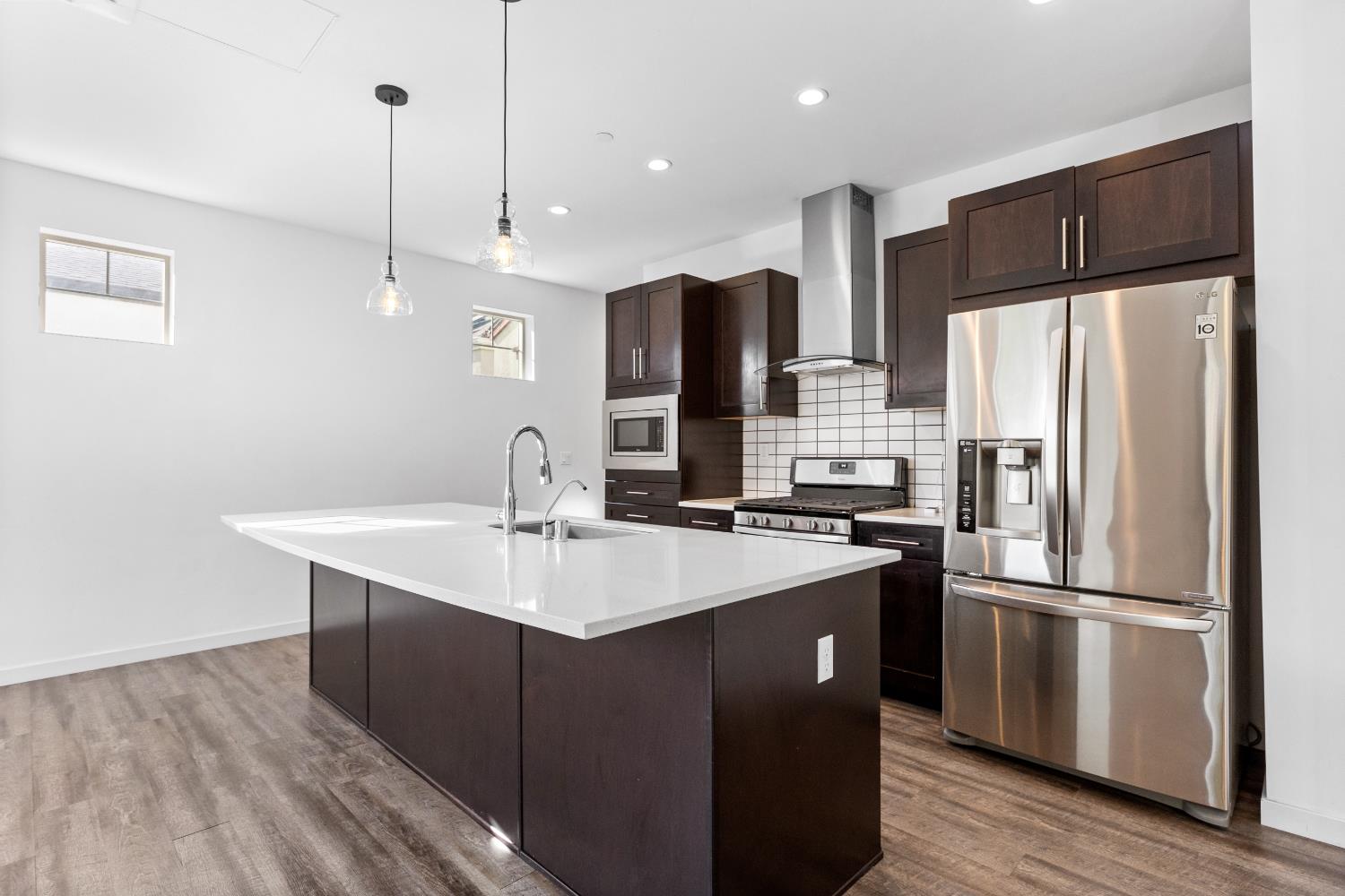 2643 Cleat Lane, Unit 34B Sacramento, CA 95818 - Photo 4 of 39 a kitchen with stainless steel appliances a sink a refrigerator a center island and wooden floor