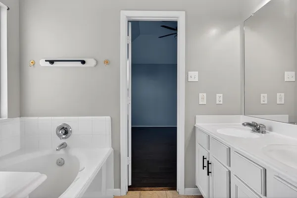 a bathroom with a tub a sink and mirror