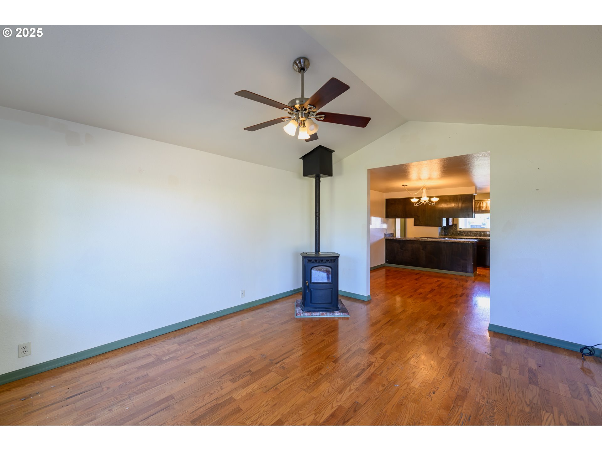 3854 Jasper Road Springfield, OR 97478 - Photo 17 of 33 a view of a room with wooden floor a ceiling fan and a kitchen view