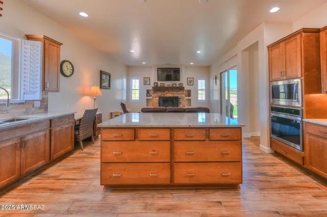 a large kitchen with kitchen island granite countertop wooden cabinets a sink and stainless steel appliances