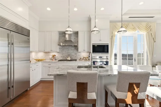 a kitchen with stainless steel appliances kitchen island granite countertop a refrigerator a stove a sink a dining table and chairs with wooden floor