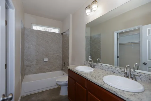 a bathroom with a granite countertop sink a toilet a bathtub and shower