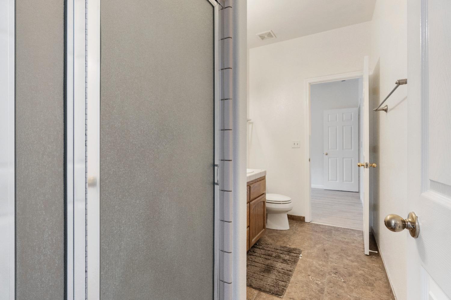 6864 Rodeo Drive Sanger, CA 93657 - Photo 31 of 48 a bathroom with a granite countertop toilet and a shower