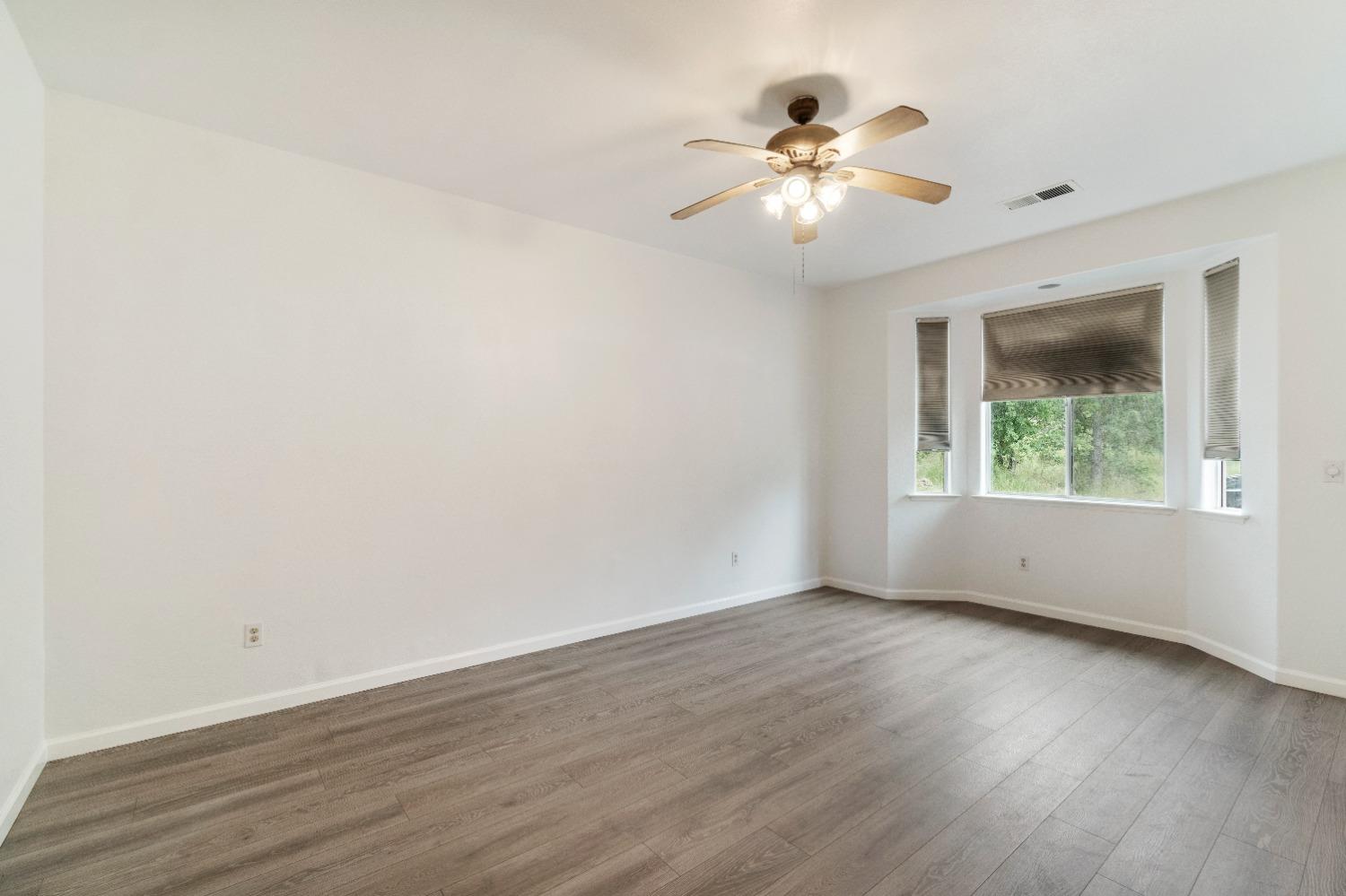 6864 Rodeo Drive Sanger, CA 93657 - Photo 32 of 48 an empty room with wooden floor chandelier fan and windows