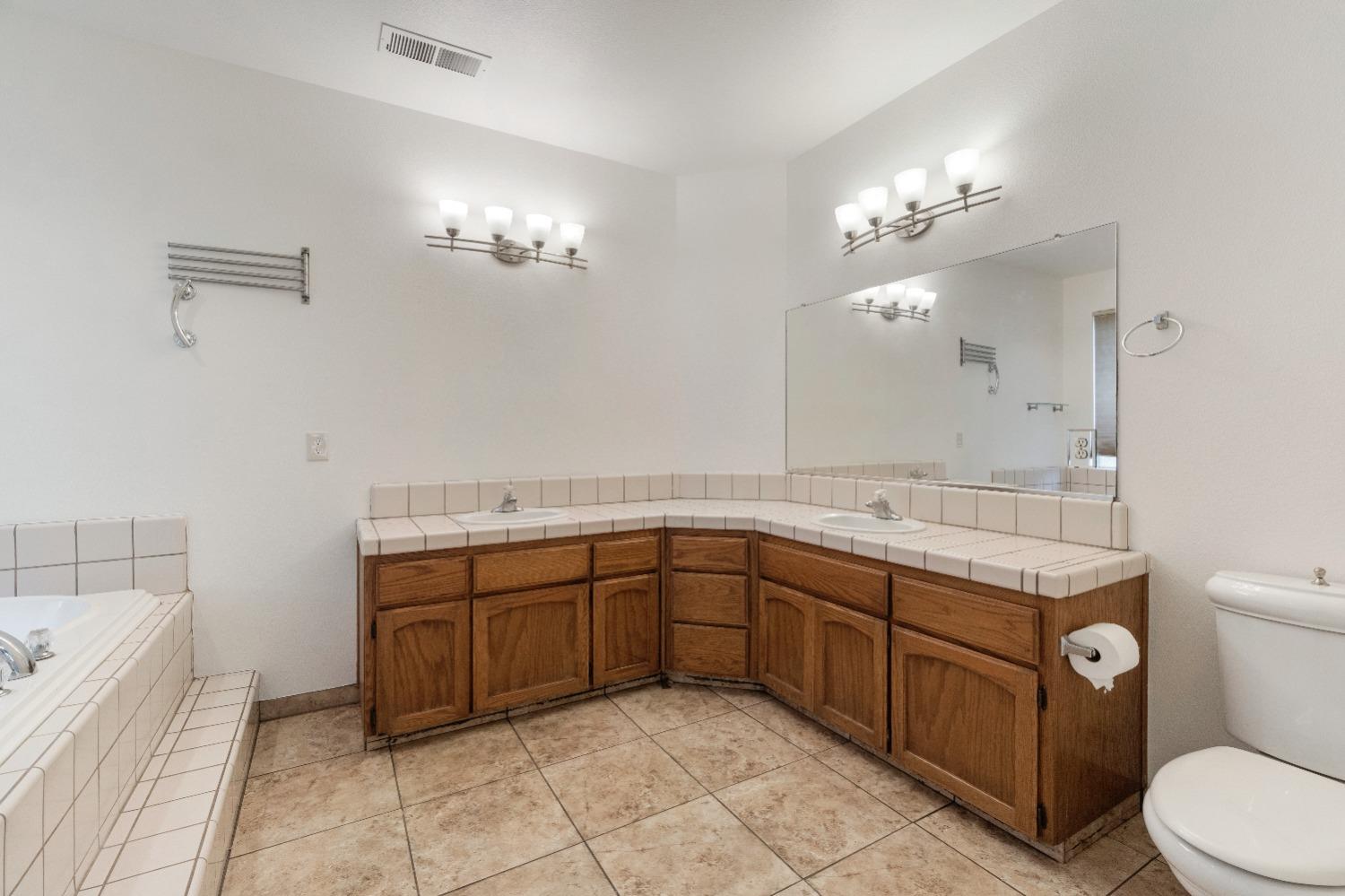 6864 Rodeo Drive Sanger, CA 93657 - Photo 38 of 48 a spacious bathroom with a granite countertop sink a toilet mirror and bathtub