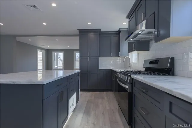 a kitchen with stainless steel appliances granite countertop a sink a stove and a wooden floors