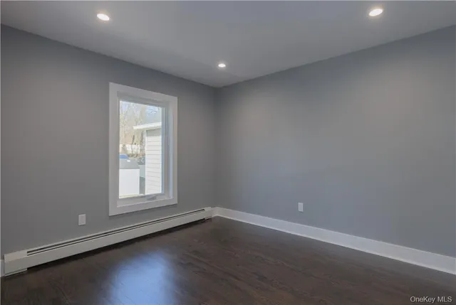 an empty room with wooden floor and window
