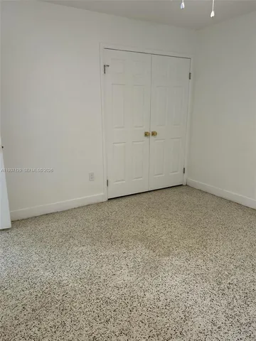 an empty room with a chandelier fan and windows