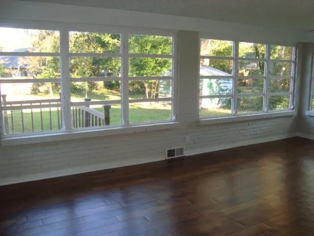 a view of an empty room with wooden floor and a window