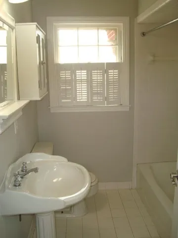 a bathroom with a sink a window and a shower