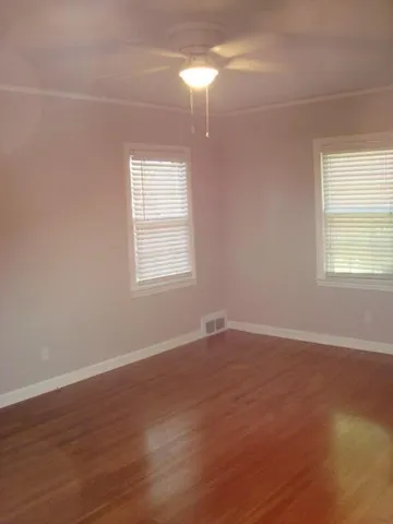 an empty room with wooden floor and windows