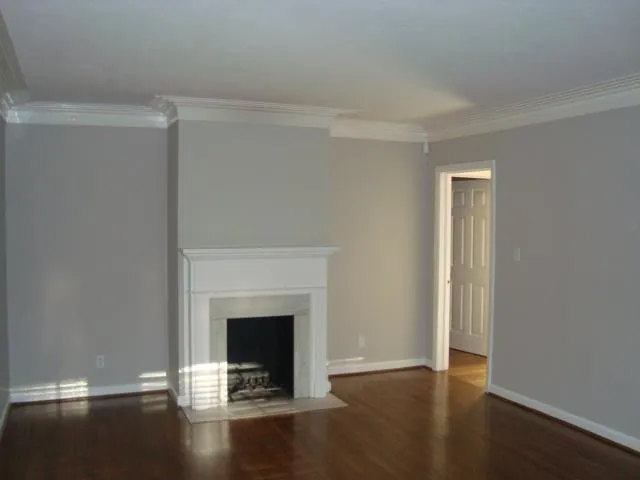 a view of an empty room with wooden floor and a fireplace